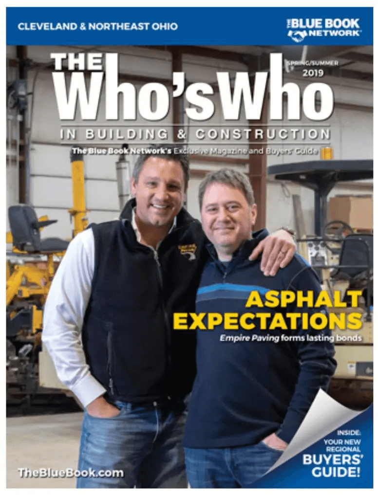Two smiling men stand together in a workshop, one with his arm around the other. The magazine cover headline reads Asphalt Expectations: Empire Paving—an Asphalt Contractor forming lasting bonds. Industrial equipment is visible in the background.