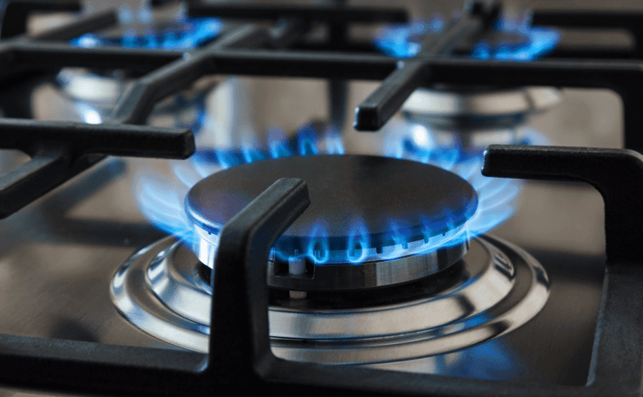 Close-up of a gas stove with blue flames visible on multiple burners, highlighting the importance of gas safety to prevent any potential leaks.