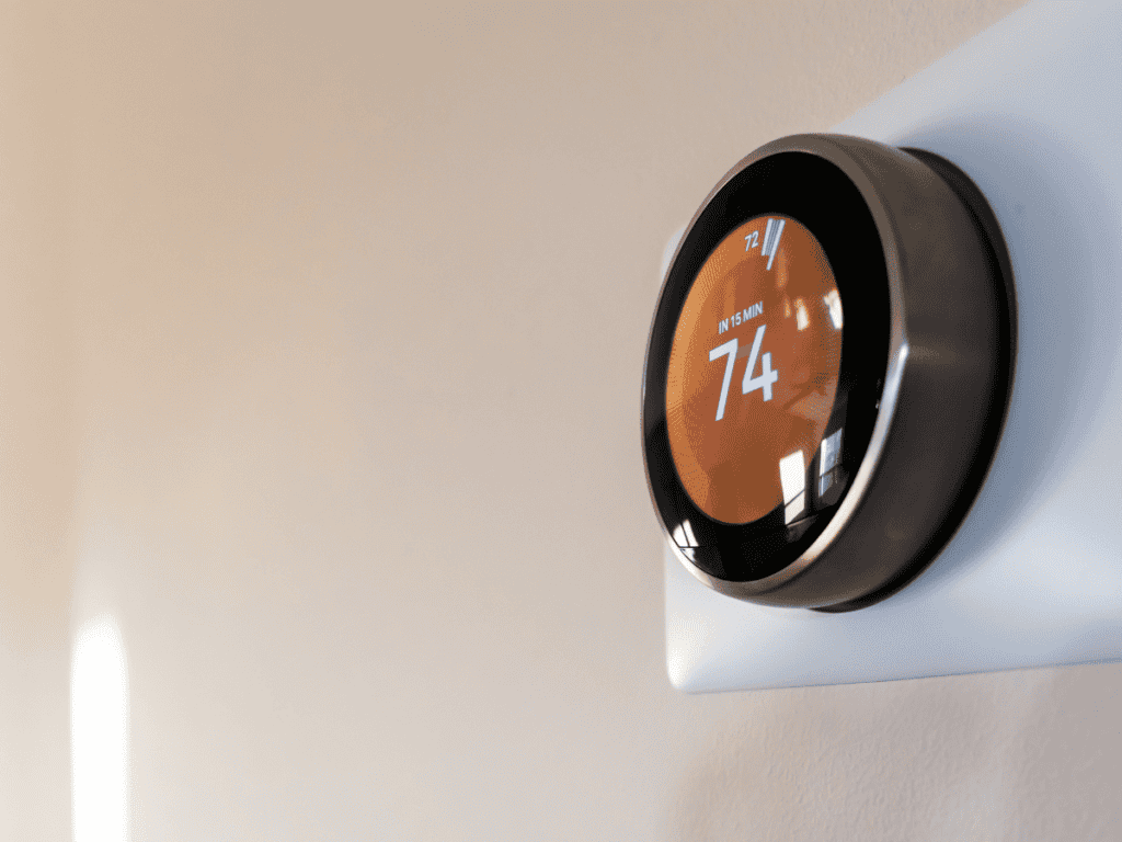 A modern digital thermostat on a wall showcases the latest in smart HVAC systems, displaying a temperature of 74 degrees Fahrenheit.