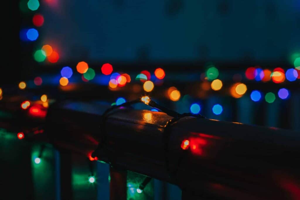 String of multicolored holiday lights wrapped around a railing in a dimly lit setting, decked to perfection for the festive season.