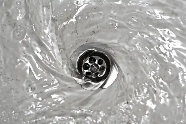 Water swirling down a metal drain in a sink creates a mesmerizing vortex pattern, reminiscent of nature's art. For persistent issues like clogged drains, consider reaching out to experts like JF Plumbing or explore simple DIY fixes to keep the flow seamless.