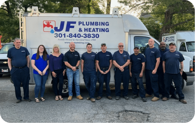 Group Of Ten People Standing In Front Of A Plumbing And Heating Company Truck, All Wearing Blue Uniforms Except One Person In Casual Attire.