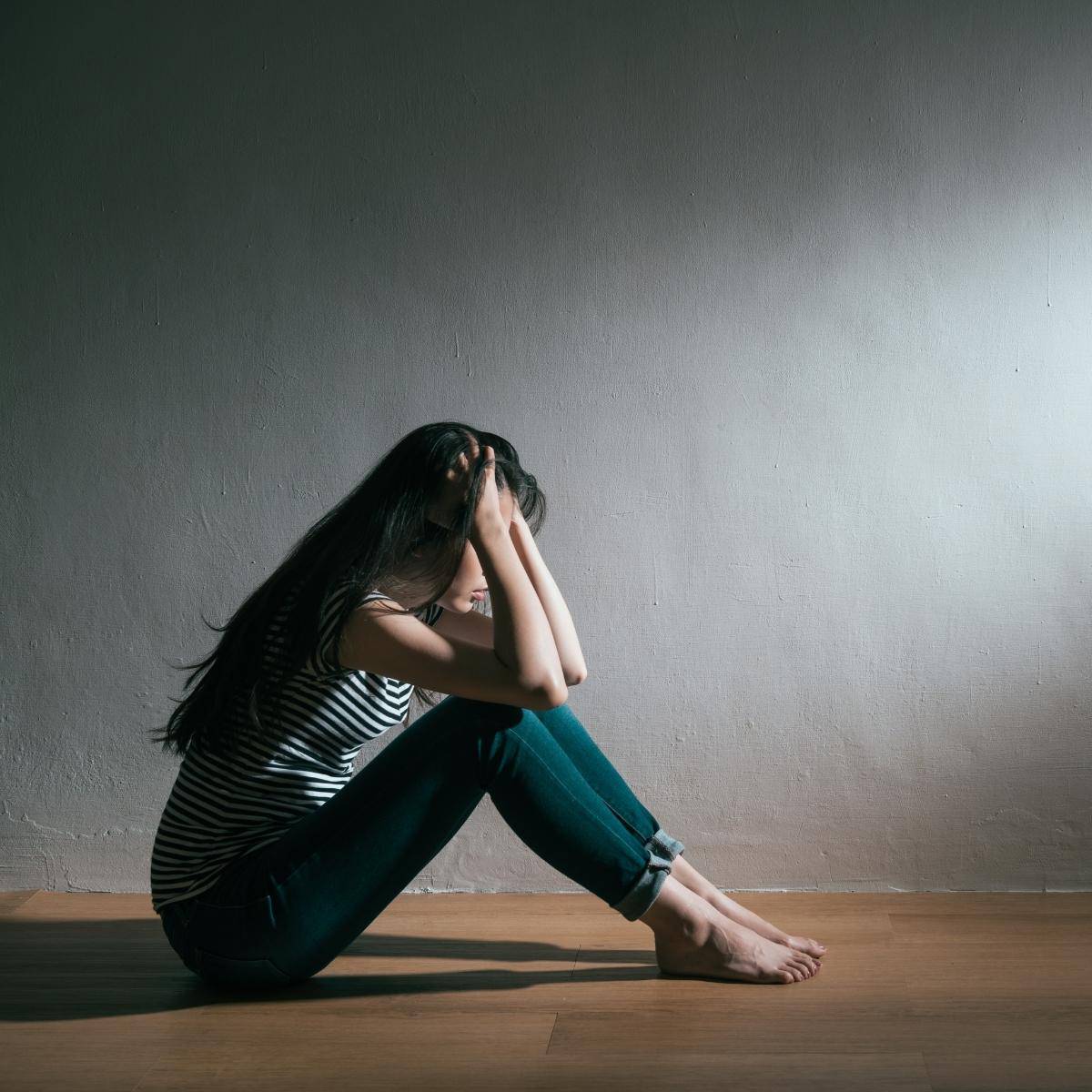 Depression, lady sitting on floor with hands on her head, she is slim but still depressed