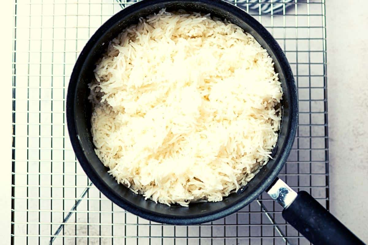 Cooked rice in a saucepan on a cooling rack