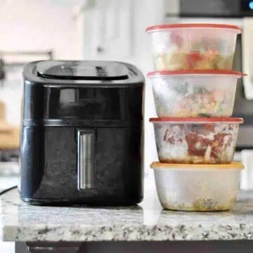 air fryer and several frozen meals in containers on a counter.
