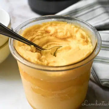 bowl of ninja creami mango sorbet with a spoon in it, napkin, stack of bowls.