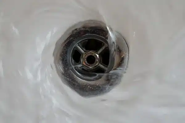 Water swirling around a metal drain in Van Nuys, CA, creates a visible vortex as it flows down—a classic scene before expert Rooter Services step in.