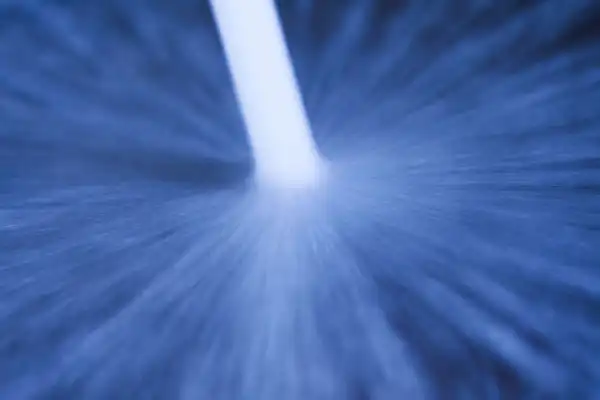 A close-up view of Hydro Jetting in Van Nuys, CA shows a white stream of water being sprayed at high pressure against a blue surface, creating a striking radial splatter pattern.