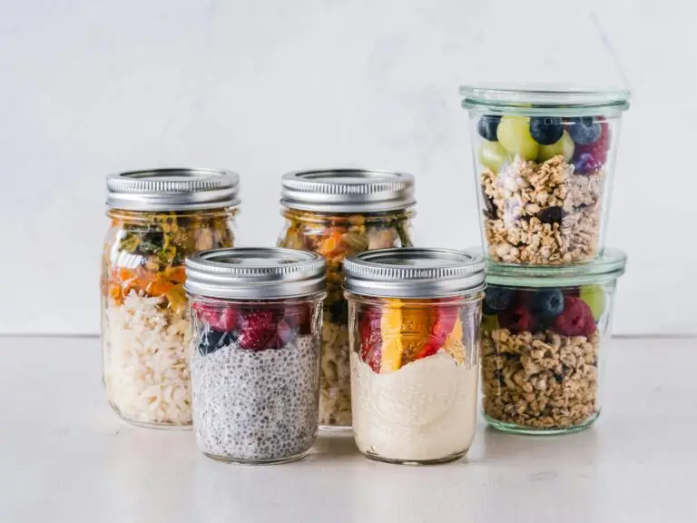 6 mason jars filled with meal prep, some with oats and berries, other with chiaseed pudding and berries, and other with grains, legumes and vegetables.
