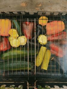 A colorful array of plant-based vegetables, including bell peppers, zucchini, and squash, grilling on a barbecue, perfect for a healthy and nutritious plant-based barbecue feast.