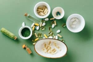 A variety of supplements, including capsules, pills, and powders, displayed on a green background. Learn how to identify safe supplements and understand supplement regulation in Europe and the U.S.