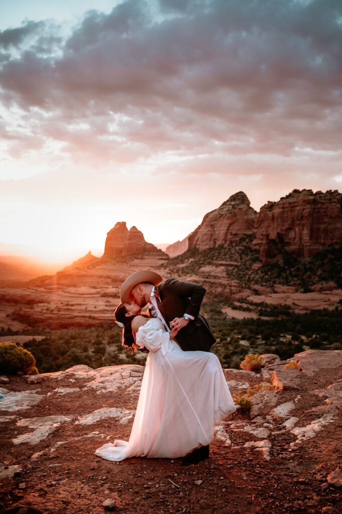 Bride and groom kiss with a dip at sunset during their Sedona elopement wedding