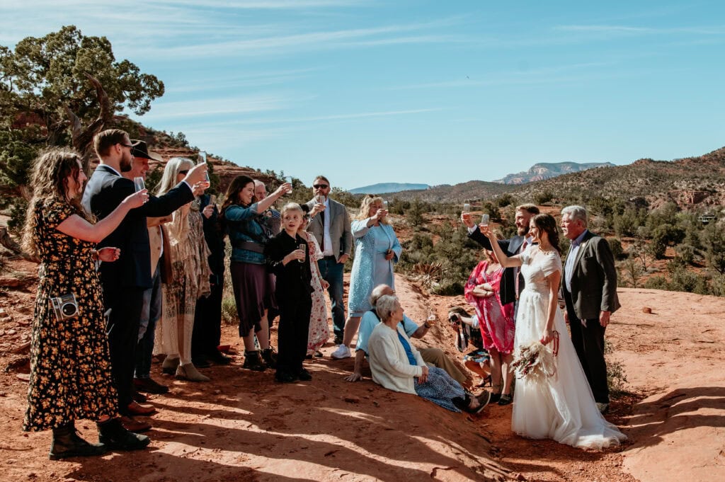 couple and family raise their glasses in a toast during their Sedona elopement