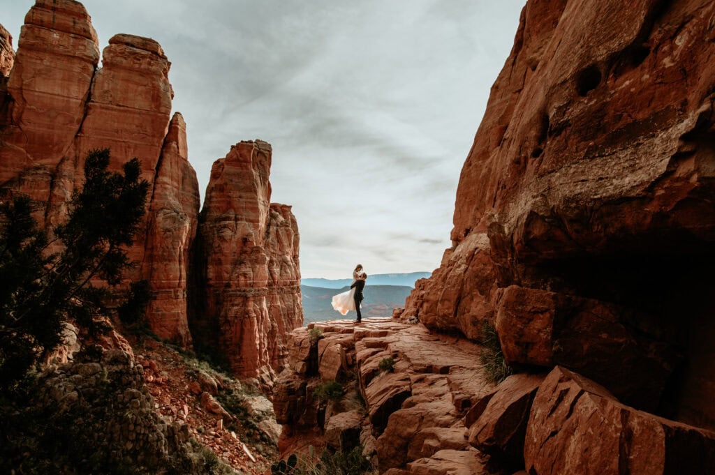 Groom lifting bride framed by the red rocks during their Arizona elopement