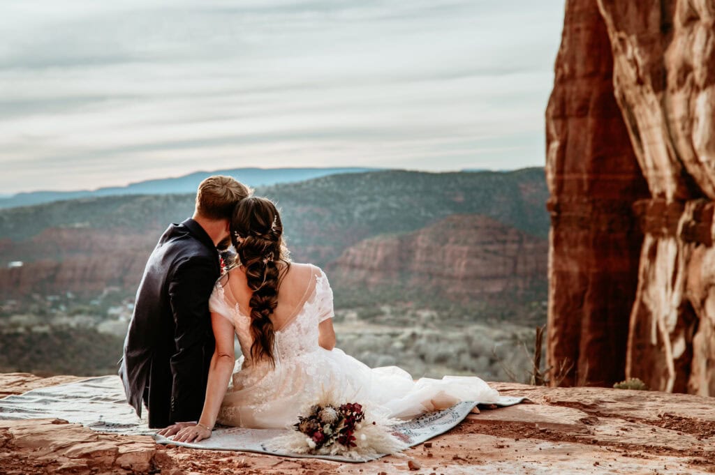 couple sitting on a blanket looking at the view during their Sedona elopement by Arizona elopement photographer Stratus Adventure Photography