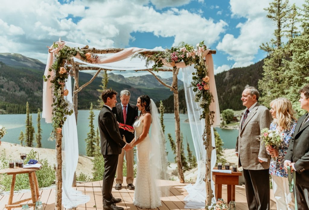 Bride and groom under aspen chuppah overlooking Lake San Cristobal during Lake City wedding