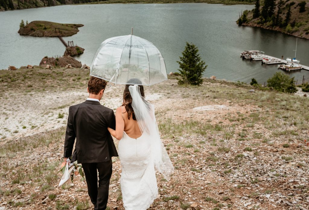 Bride and groom walking arm in arm down a hill to the water at Lake San Cristobal