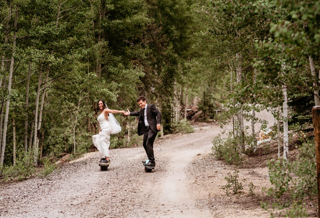 Couple holding hands riding their one wheels up a gravel road