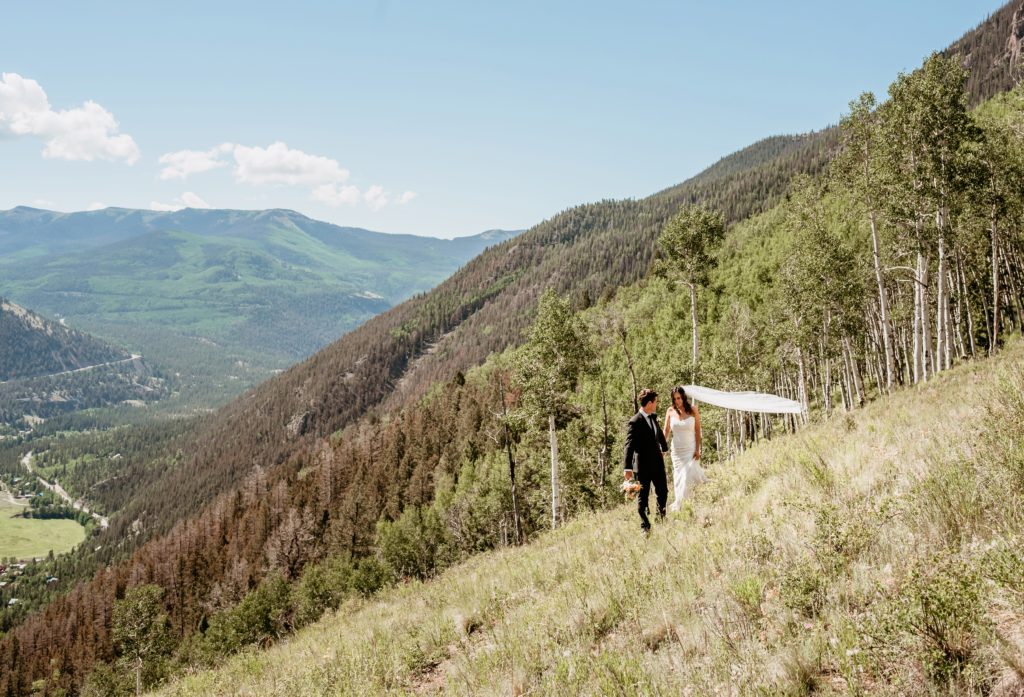 Groom leading bride across the mountain top on their Colorado elopement