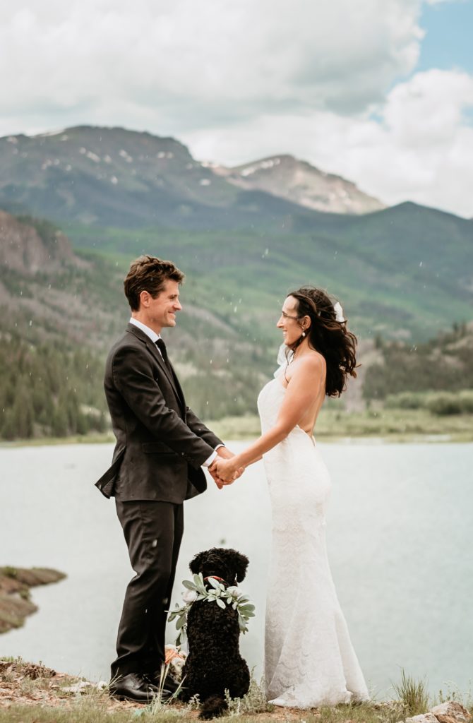 Bride and groom holding hands over their flower pup as the rain begins to fall on their Lake San Cristobal wedding day