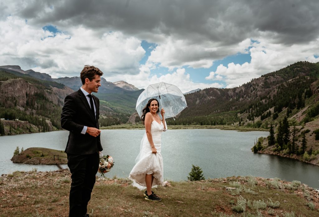 laughing at the rain with a clear umbrella during a summer rain storm at Lake San Cristobal elopement