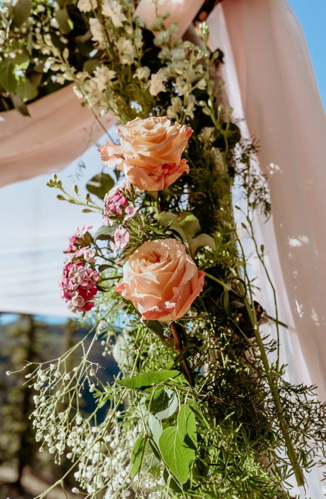 Beautiful roses and greenery on corner of chuppah at Lake San Cristobal wedding