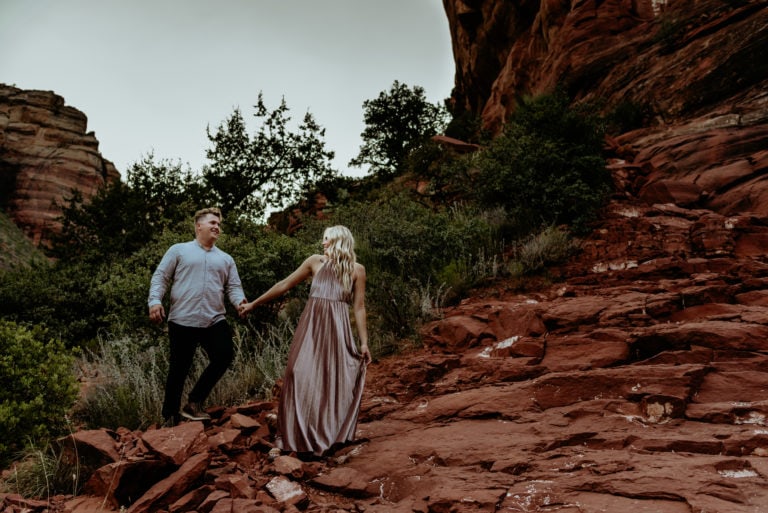 Couple walking hand in hand through red rock canyon