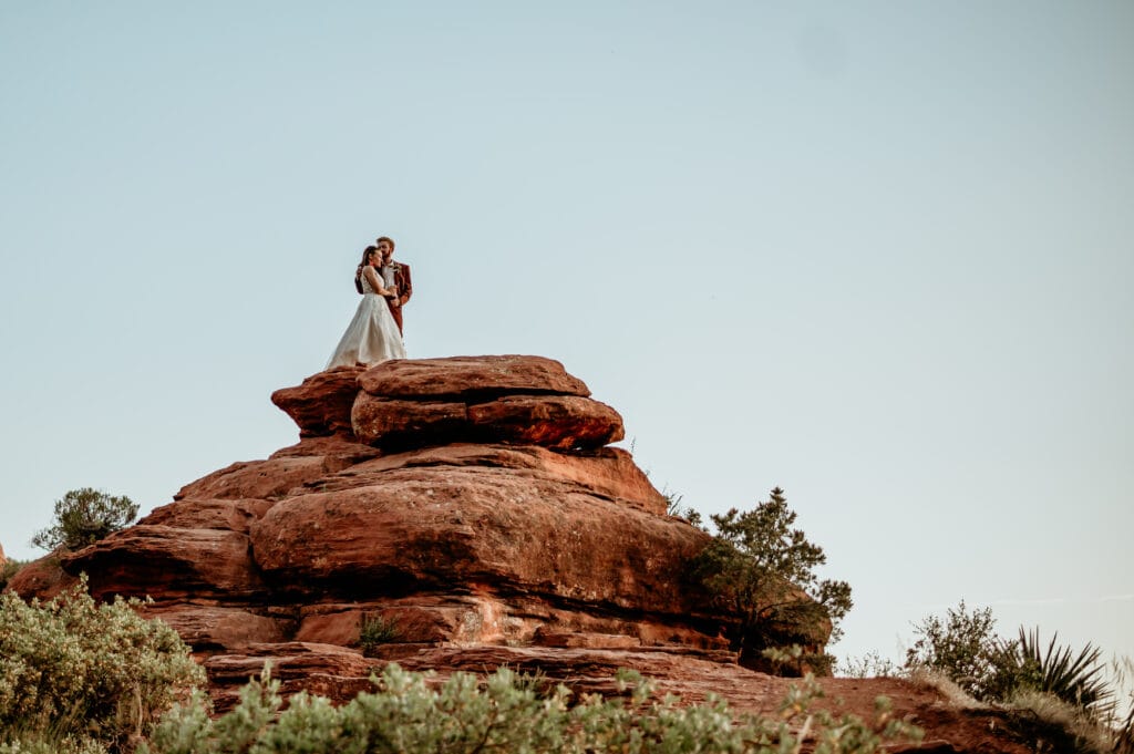 Eloping couple standing on the red rocks of Sedona watching the sunset