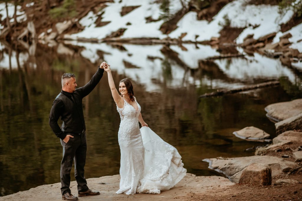Bride and groom dance at the edge of a snow capped lake in Arizona