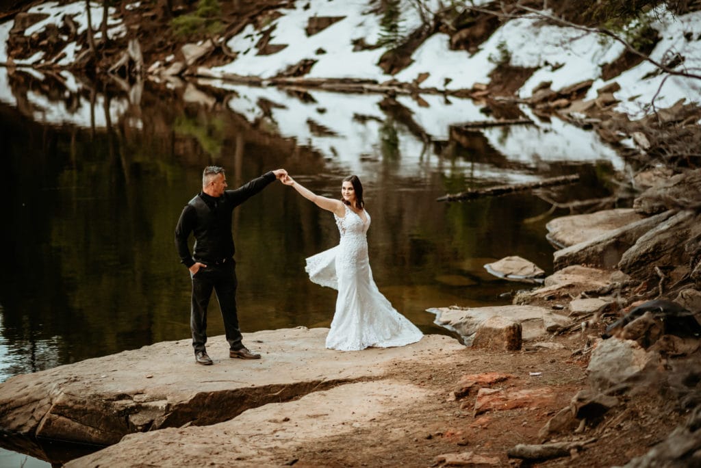 Bride's wedding dress flares out as she dances with her husband at a northern Arizona lake
