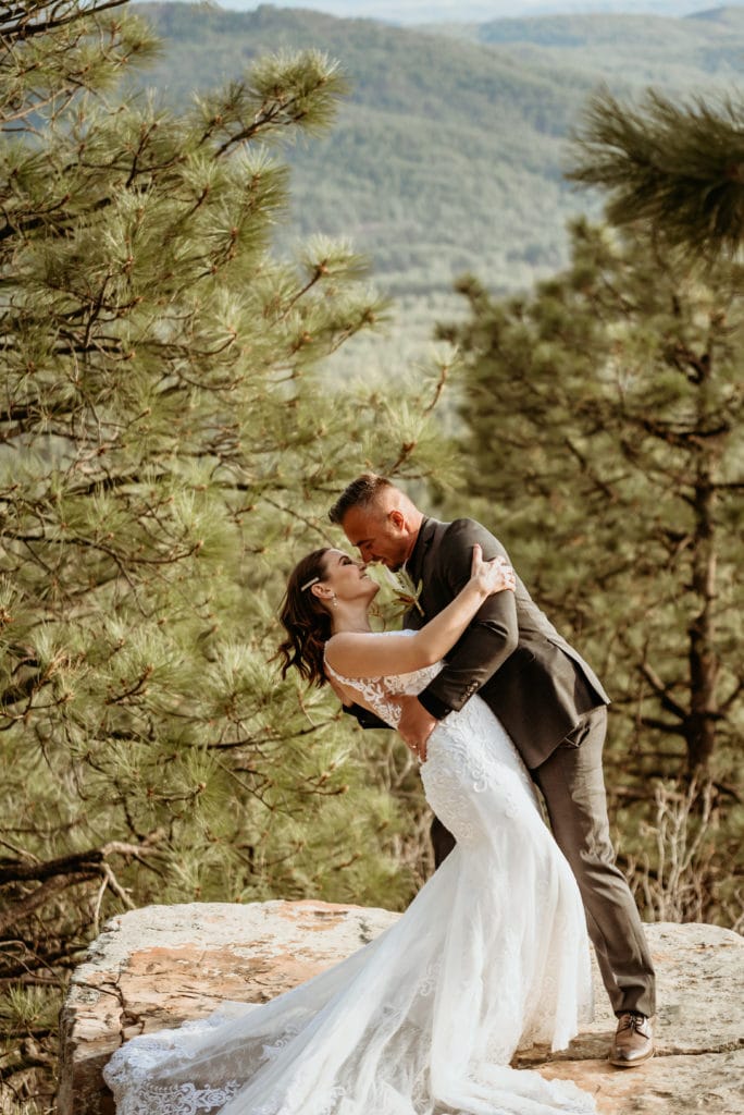 Groom dips his beautiful bride amongst the pines during their intimate elopement