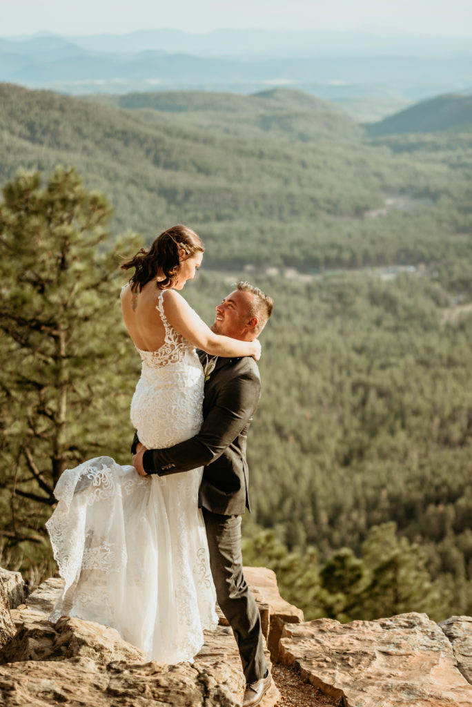 Joyful booty lift as bride smiles at her husband during their gorgeous outdoor wedding