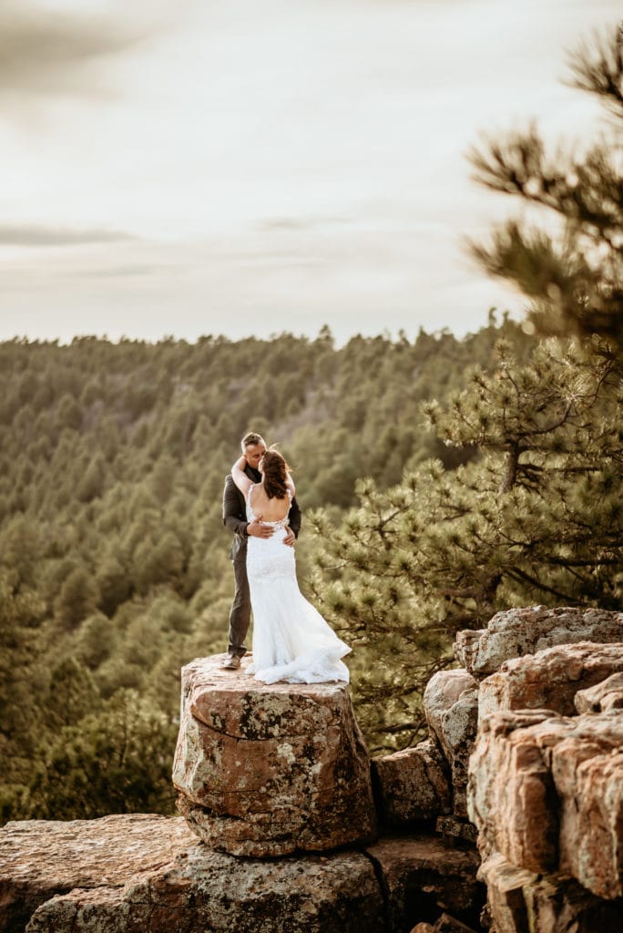 Husband holding his new wife on the edge of the Mogollon Rim during their northern Arizona wedding