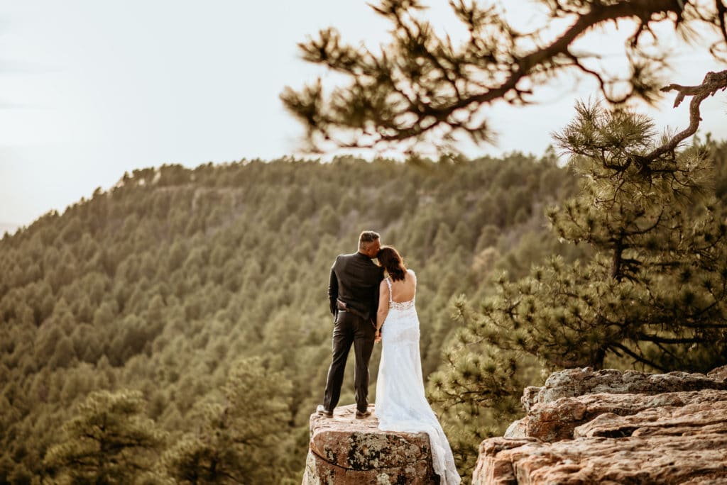 Groom kisses his wife's head as they look off into the distance during their incredible Mogollon Rim wedding