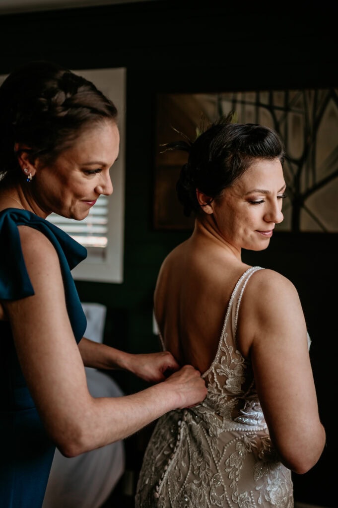 sister fastens bride's dress before her elopement