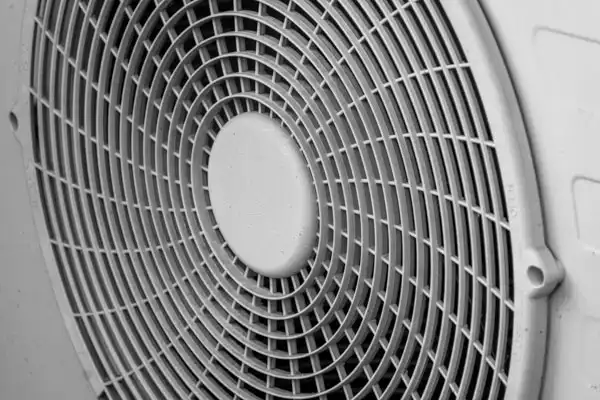 Close-up of a circular fan grille with a concentric grid pattern, viewed from the front, showcasing its protective mesh—ideal for efficient heat pump repair.