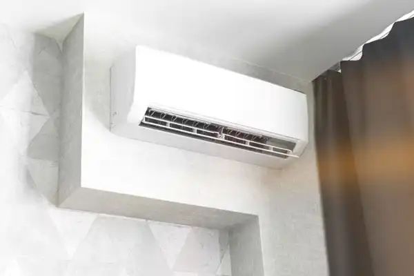 A wall-mounted air conditioner sits beside a dark curtain in the room's corner, perfectly poised for efficient cooling. If needed, expert mini split repair ensures it operates flawlessly.