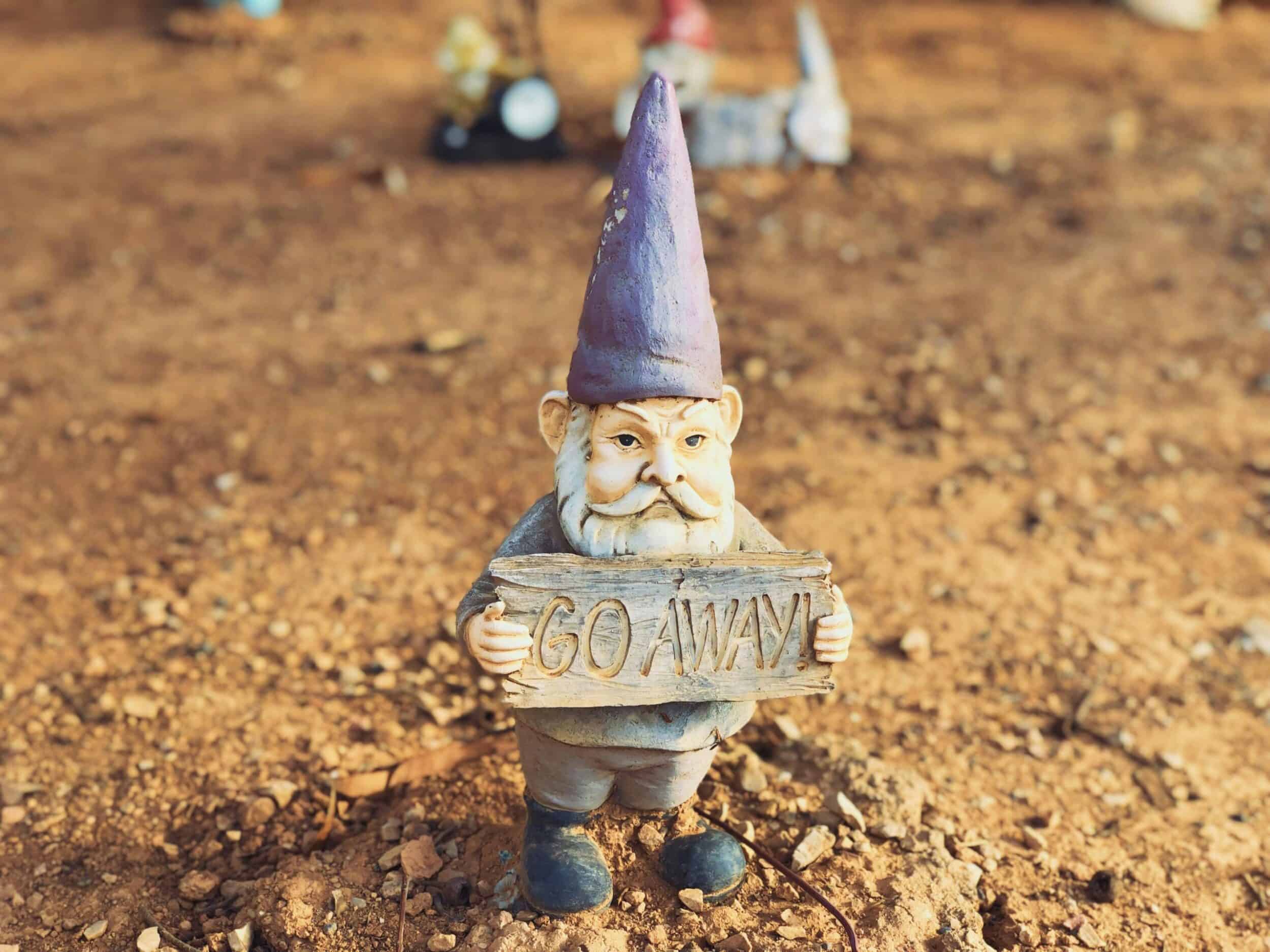 Garden gnome holding sign that says "Go Away".