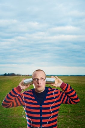 Man holding tin cans to his ears.