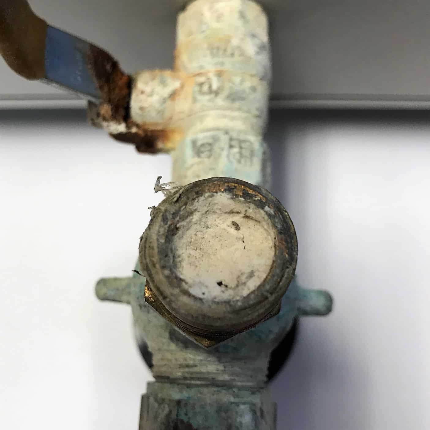 A fully blocked valve full of sediment buildup in a pipe with a rusted lever.