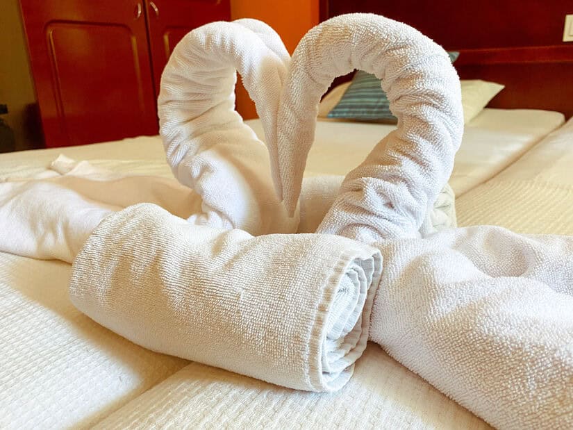 Two white hotel bath towels are folded to look like swans. Soft towels and linens are the perfect way to welcome a guest to their hotel room.