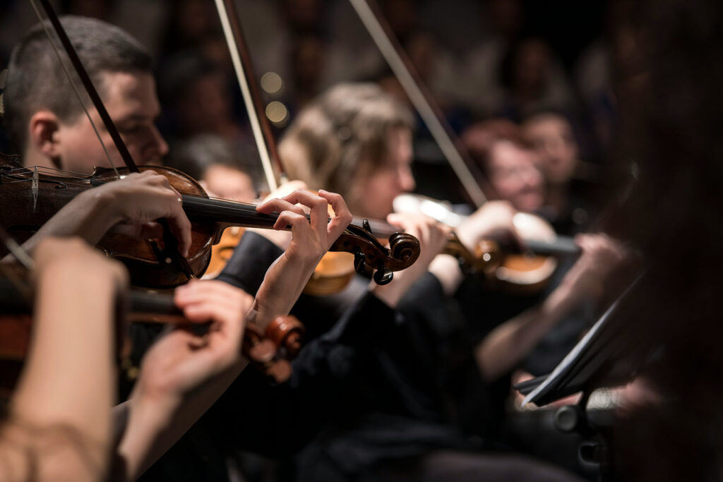 Out of focus view of the violin section playing in an orchestra.