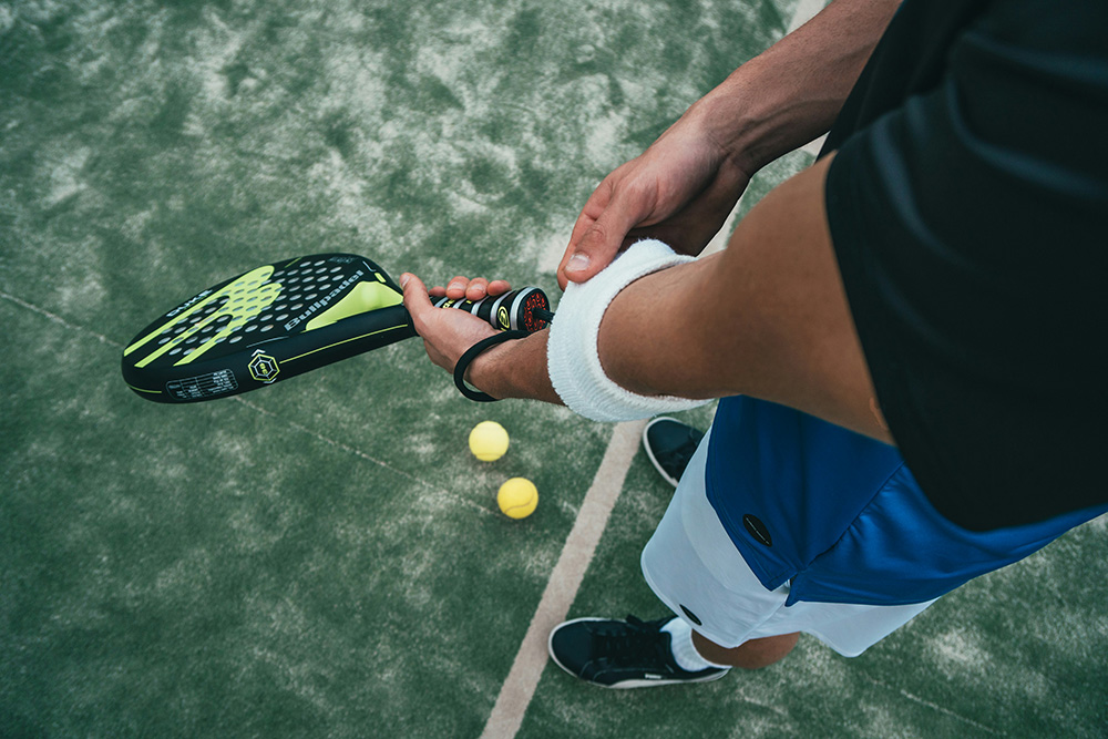 View of a man's arms as he is practicing tennis on a court.