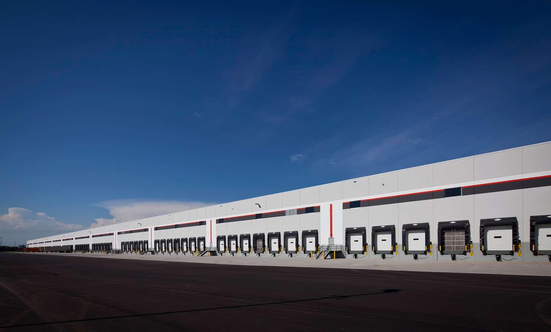 A long shot of the side of an industrial building stretching into the distance. The wall is lined with garage doors and a gate. The 750,000 SF Weber-Stephen Distribution Center was built by Keeley Construction, Inc.