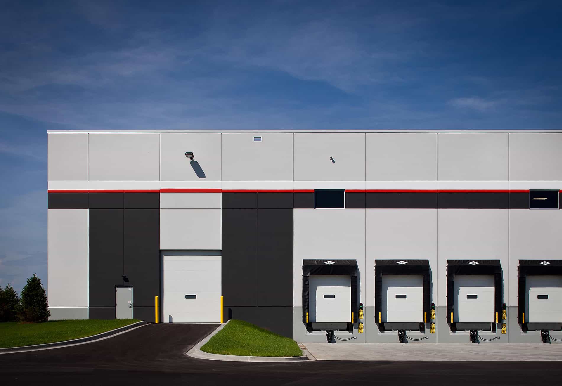 A warehouse corner with a driveway, gates and garages, which are all part of the Weber-Stephen Distribution Facility built by Keeley Construction, Inc.