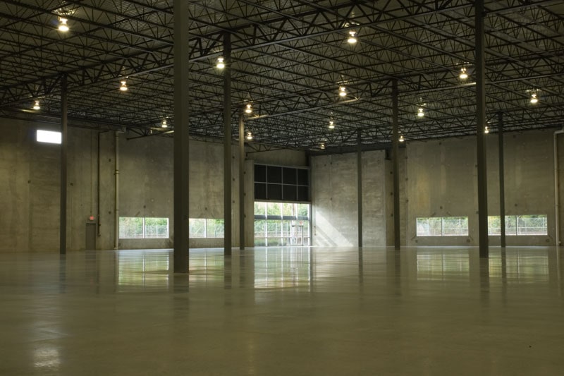 An empty, low-lit concrete warehouse has a couple of support columns and a large rectangular window in the concrete walls. This building is one of two nearly identical facilities built by Keeley Construction in the O'Hare East Business Park.