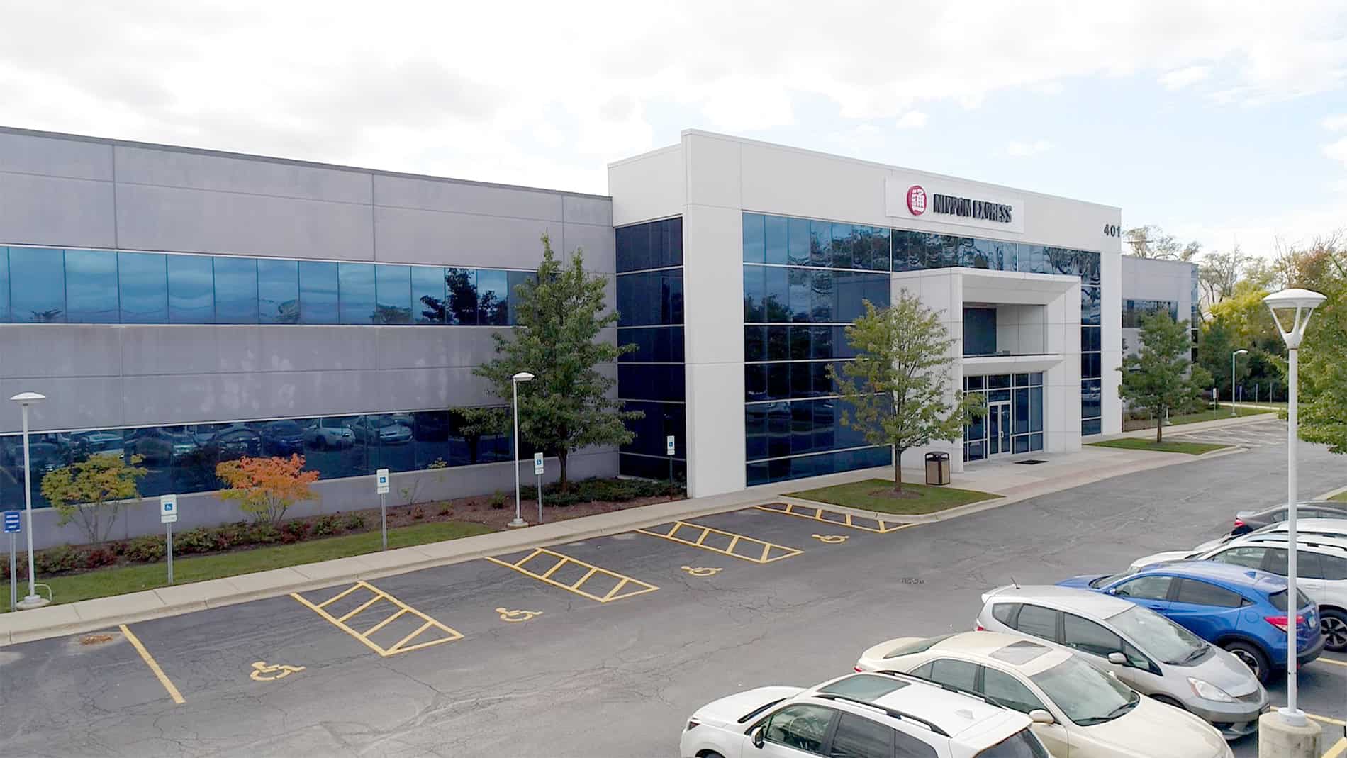 The office building and warehouse entrance has two rows of blue-reflective windows and ample parking in front.