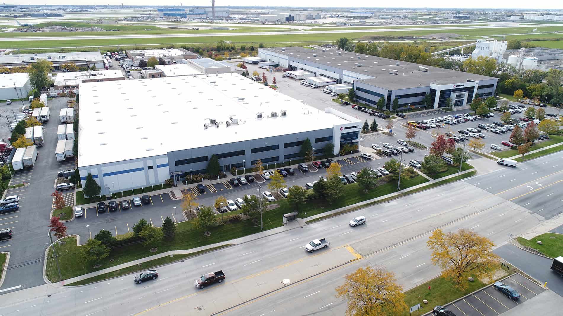 An aerial view of the Nippon Express campus shows a large, flat-roofed warehouse and side parking lot.