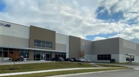 The Larch Speculative Warehouse is seen from the parking lot. The new two-story, massive building has a windowed entrance.