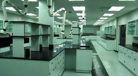 A white room full of workspaces, counters, and cabinets, lit with fluorescent overhead fixtures. This room is part of the construction management project Keeley Construction, Inc. completed for Nicoat, which makes plastic coatings.
